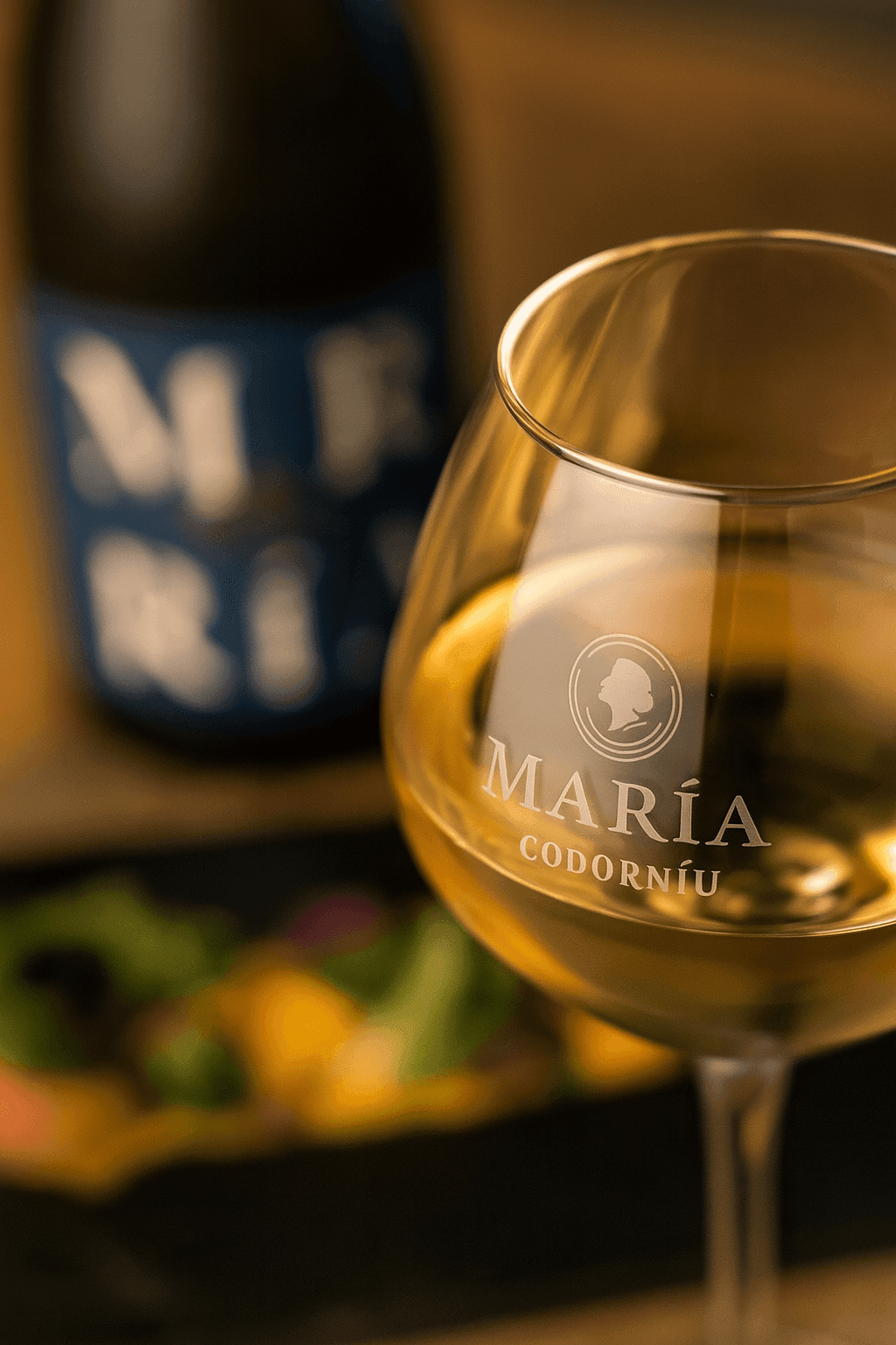 Close-up of a wine glass with gold liquid, blurred bottle and food in background.