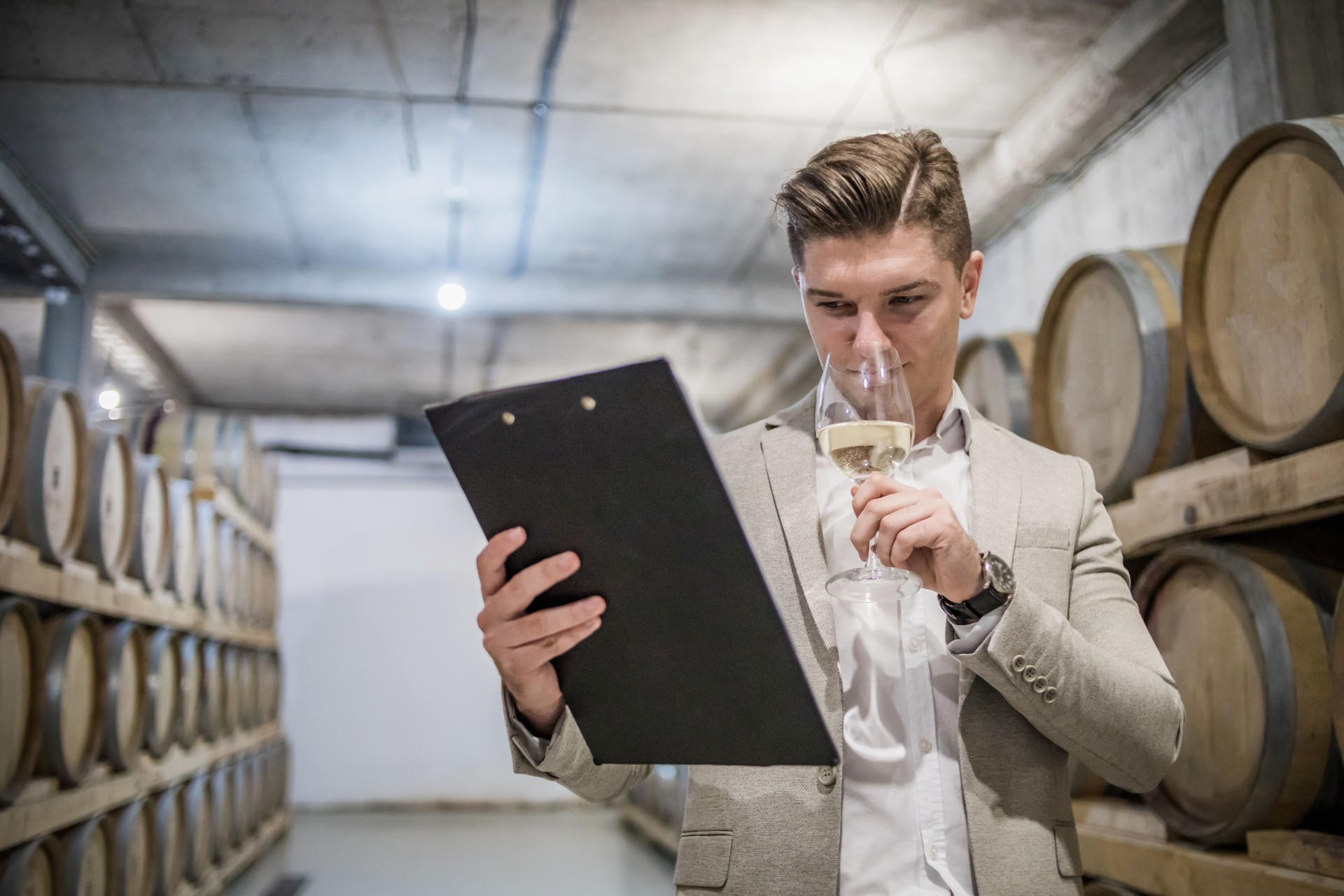Sommelier wine tasting. The owner of the winery checks the quality and stocks of wine in the wine cellar, around it are wooden barrels with quality wine. Regular inspection of the wine cellar and wine tasting.